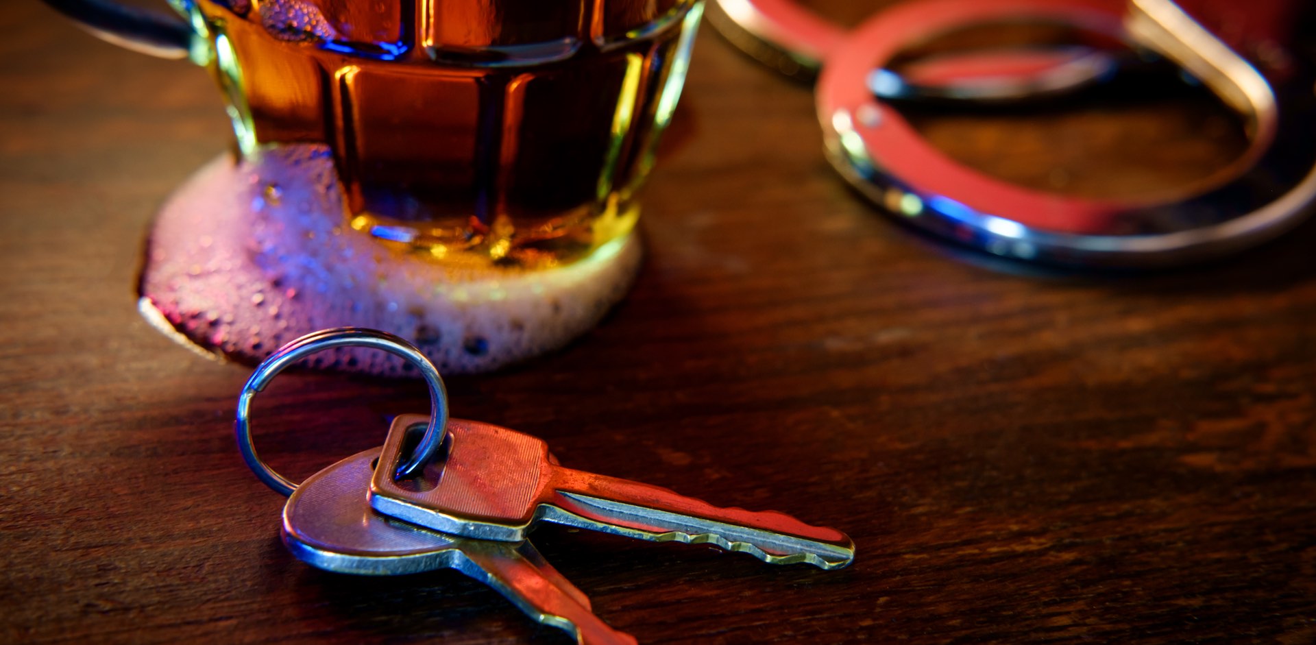 Driving while under the influence after Third DWI Offense resulted in keys on table with booze and handcuffs.
